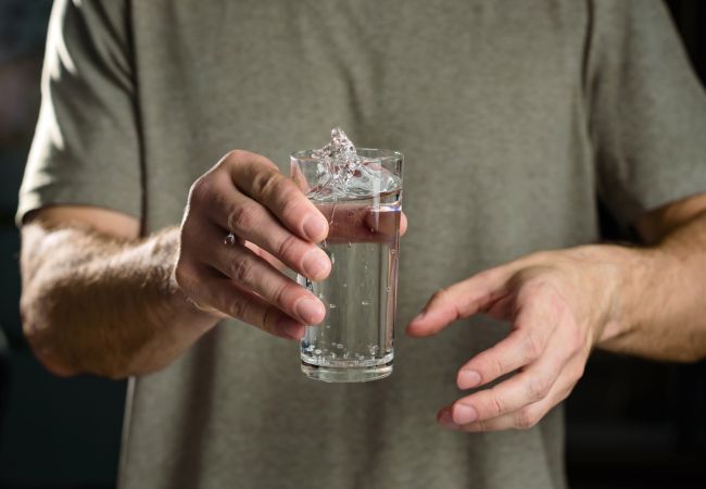 Mann hält wackeld ein Glass Wasser 