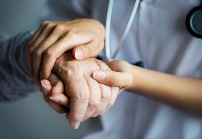 Krankenschwester hält die Hand eines alten Menschen